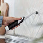 Handheld Sonic Scrubber cleaning brush being used on tiled wall, ideal for kitchen and bathroom cleaning.